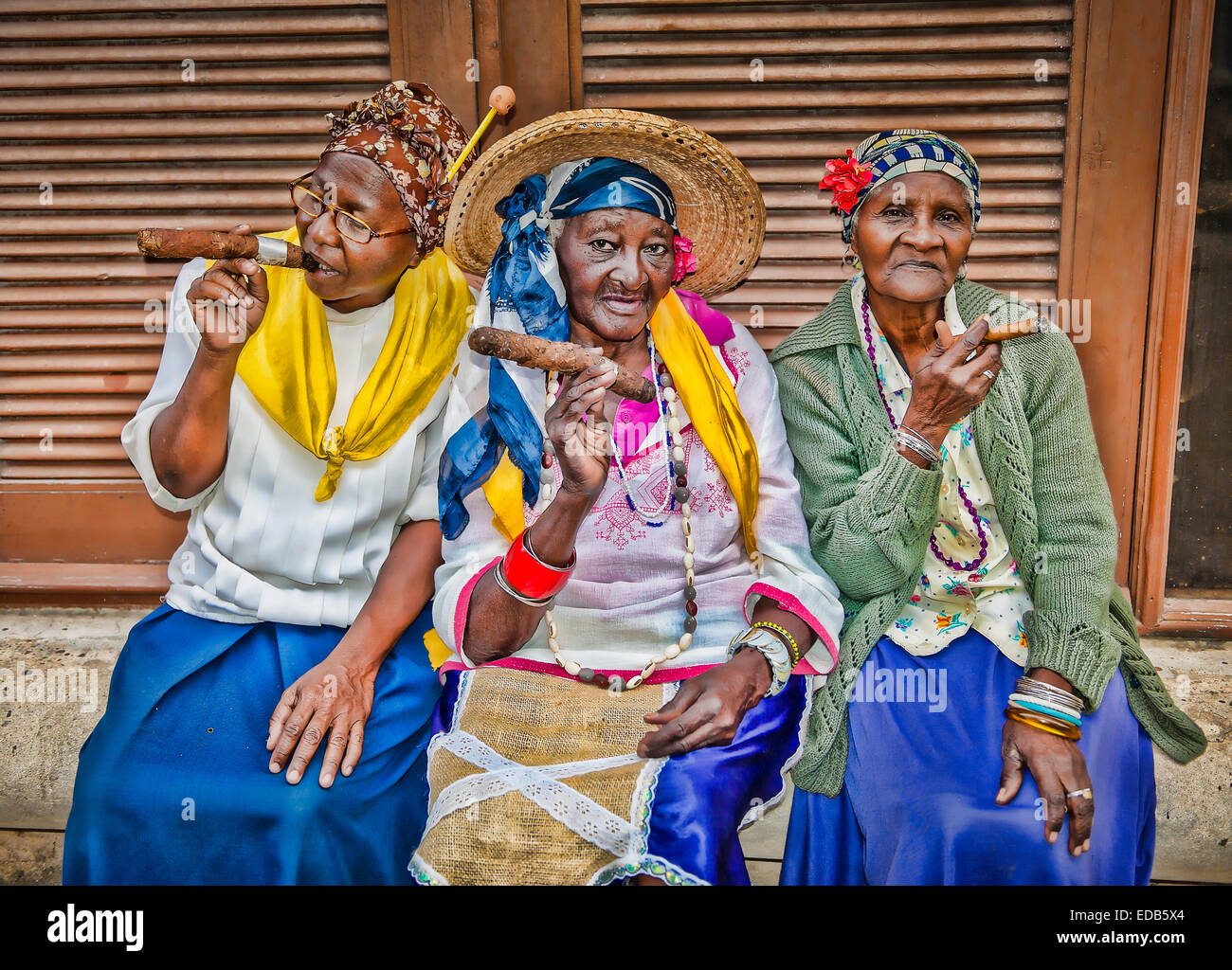 Tre vecchie Donne cubane che indossano costumi tipici fumare sigari Santeria Foto Stock