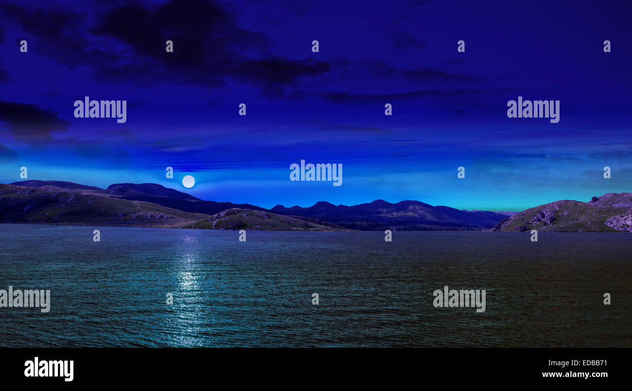 Scena notturna in montagna con la luna piena riflessa nel mare blu dell'acqua. Foto Stock