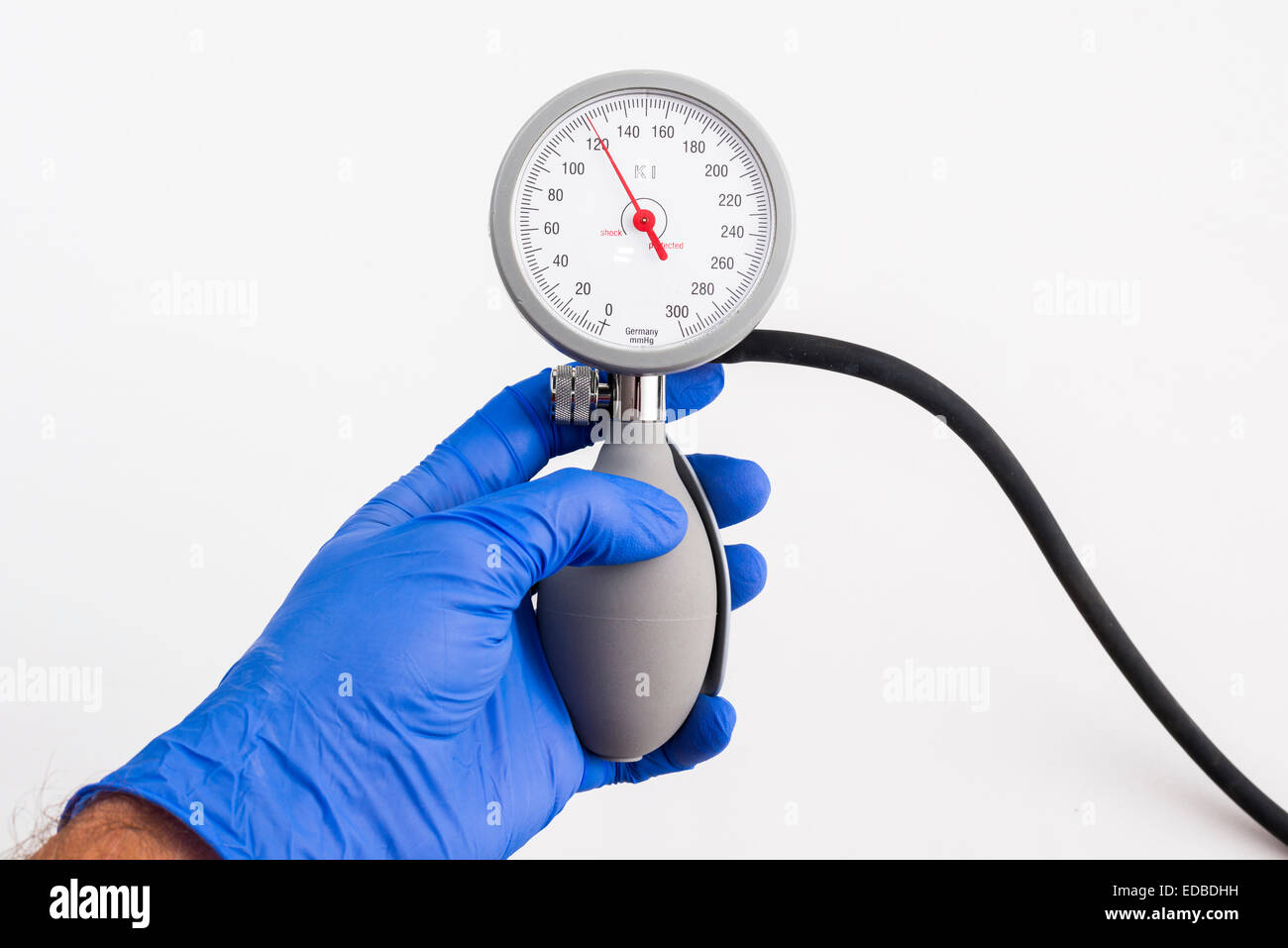 Una mano con un blu guanto medicale è in possesso di uno sfigmomanometro, sangue misuratore di pressione, che indica pressione arteriosa normale Foto Stock