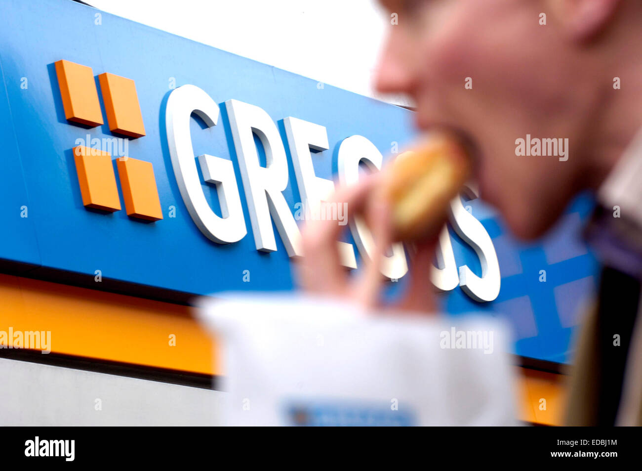 Un uomo mangiare il suo recente acquisto Greggs cibo. Foto Stock