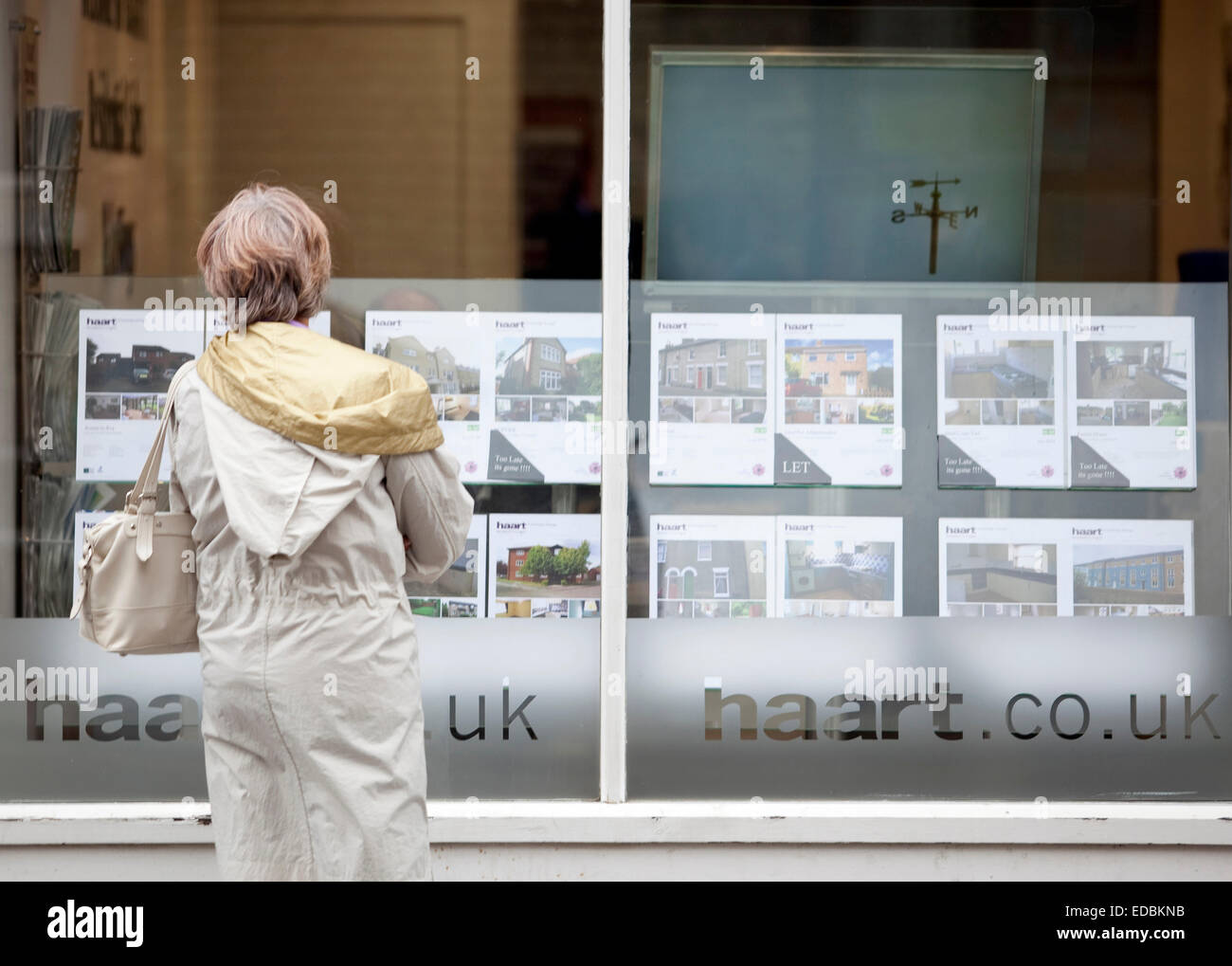 Una persona che appare nella finestra di un agente immobiliare. Foto Stock