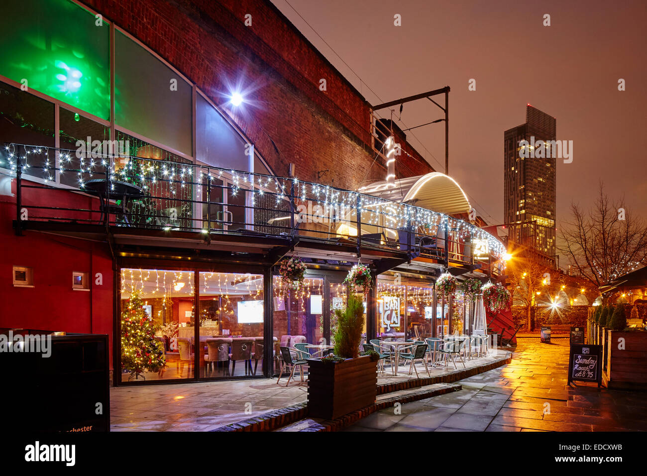 Castlefield bacino di Manchester al crepuscolo. Barca bar costruito nell'arco ferroviario viadotto con Beetham Tower dietro Foto Stock