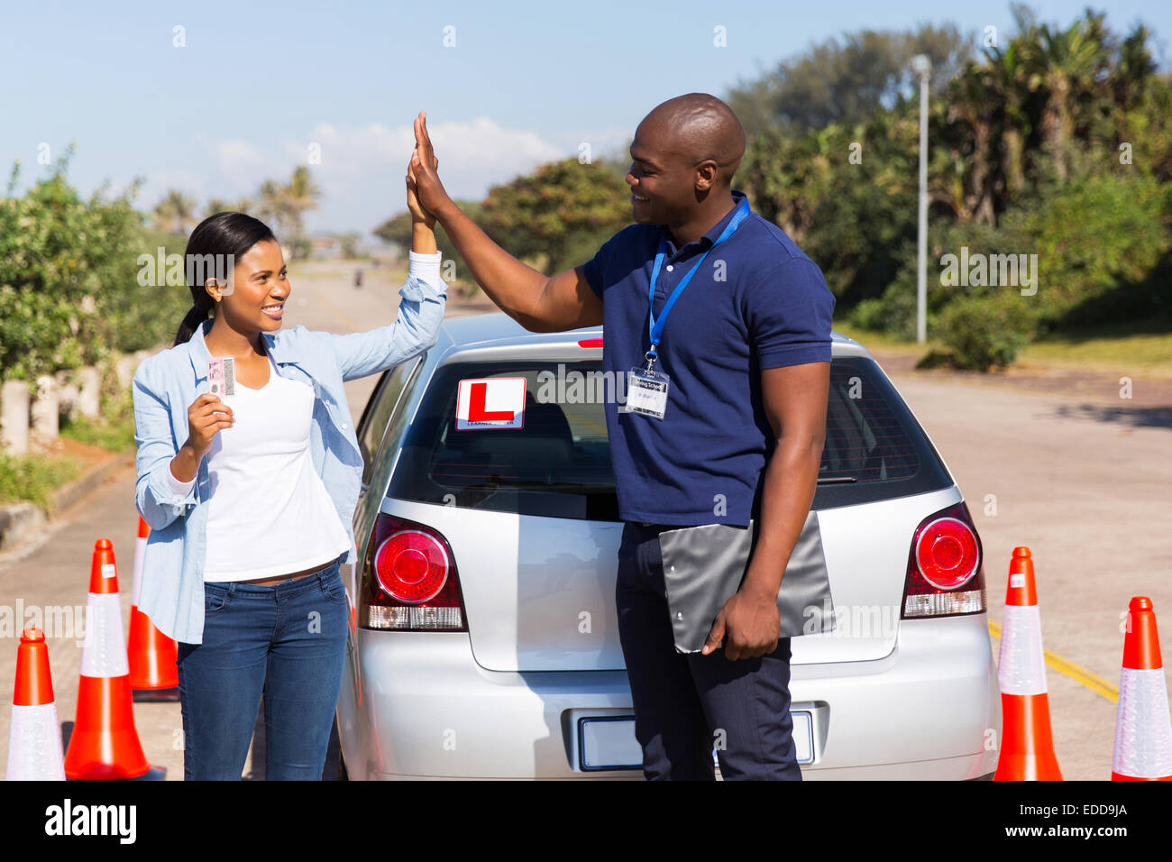 Felice ragazza africana e istruttore di guida facendo alta cinque dopo aver ottenuto la sua patente di guida Foto Stock