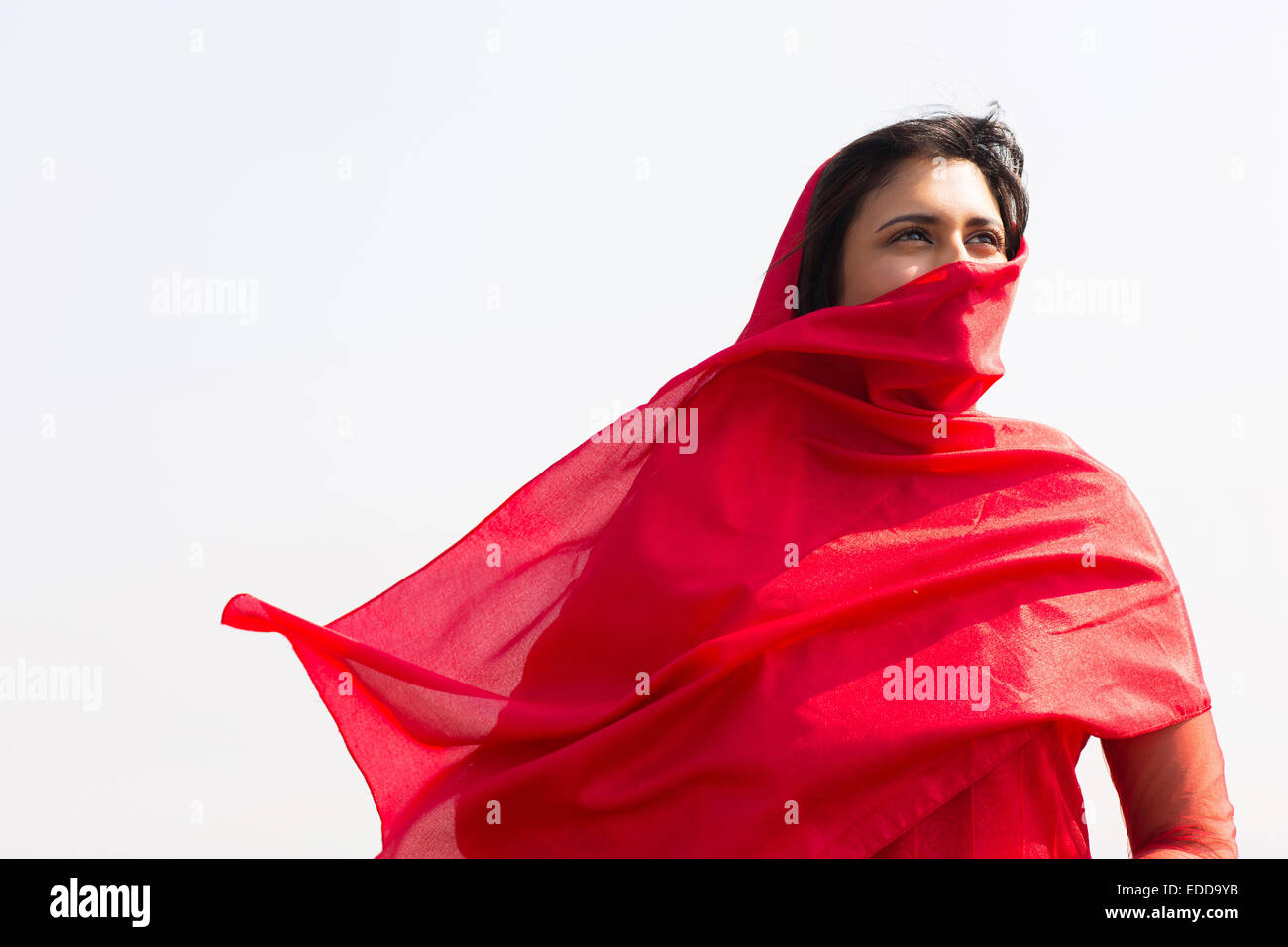 Premurosa donna indiana in sari che copre il volto con il velo Foto Stock