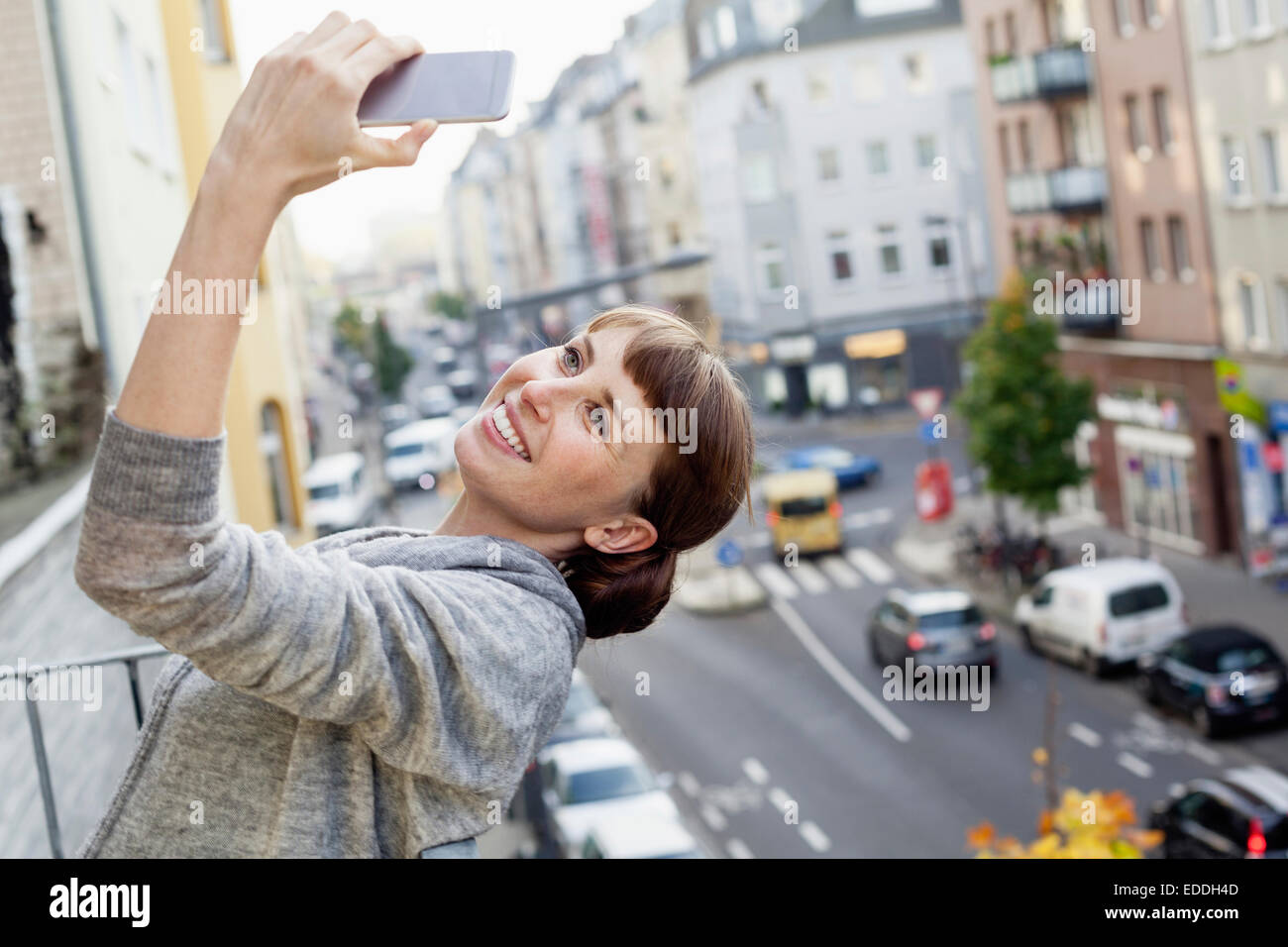 Sorridente sul balcone Pendente ritornare donna prendendo selfie Foto Stock
