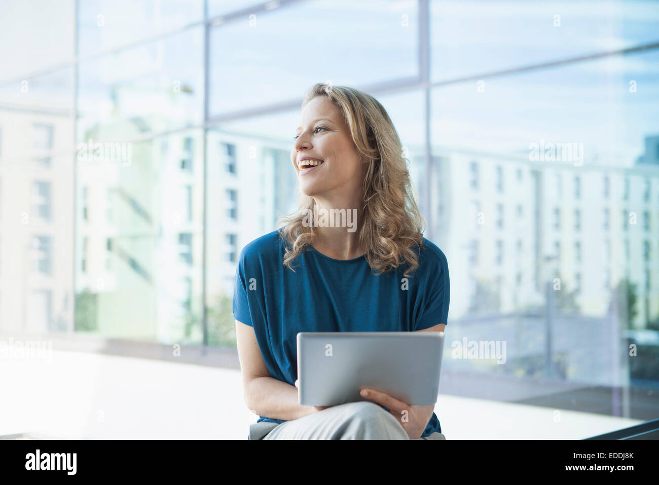 Sorridente donna matura con tavoletta digitale seduto nel suo appartamento Foto Stock