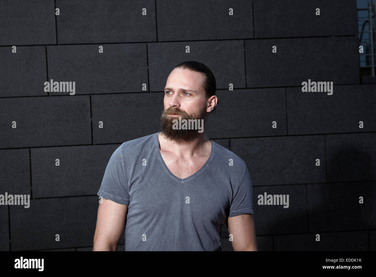 Ritratto di uomo con barba folta di fronte a uno sfondo grigio Foto Stock