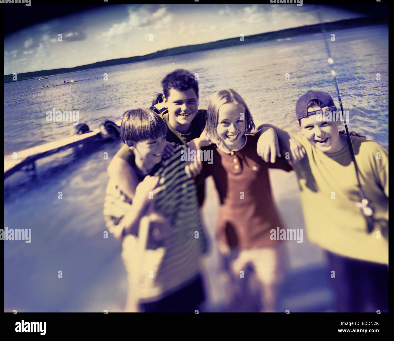 Quattro figli, pre-adolescenti ridere sulla riva del lago. La vacanza estiva. Foto Stock