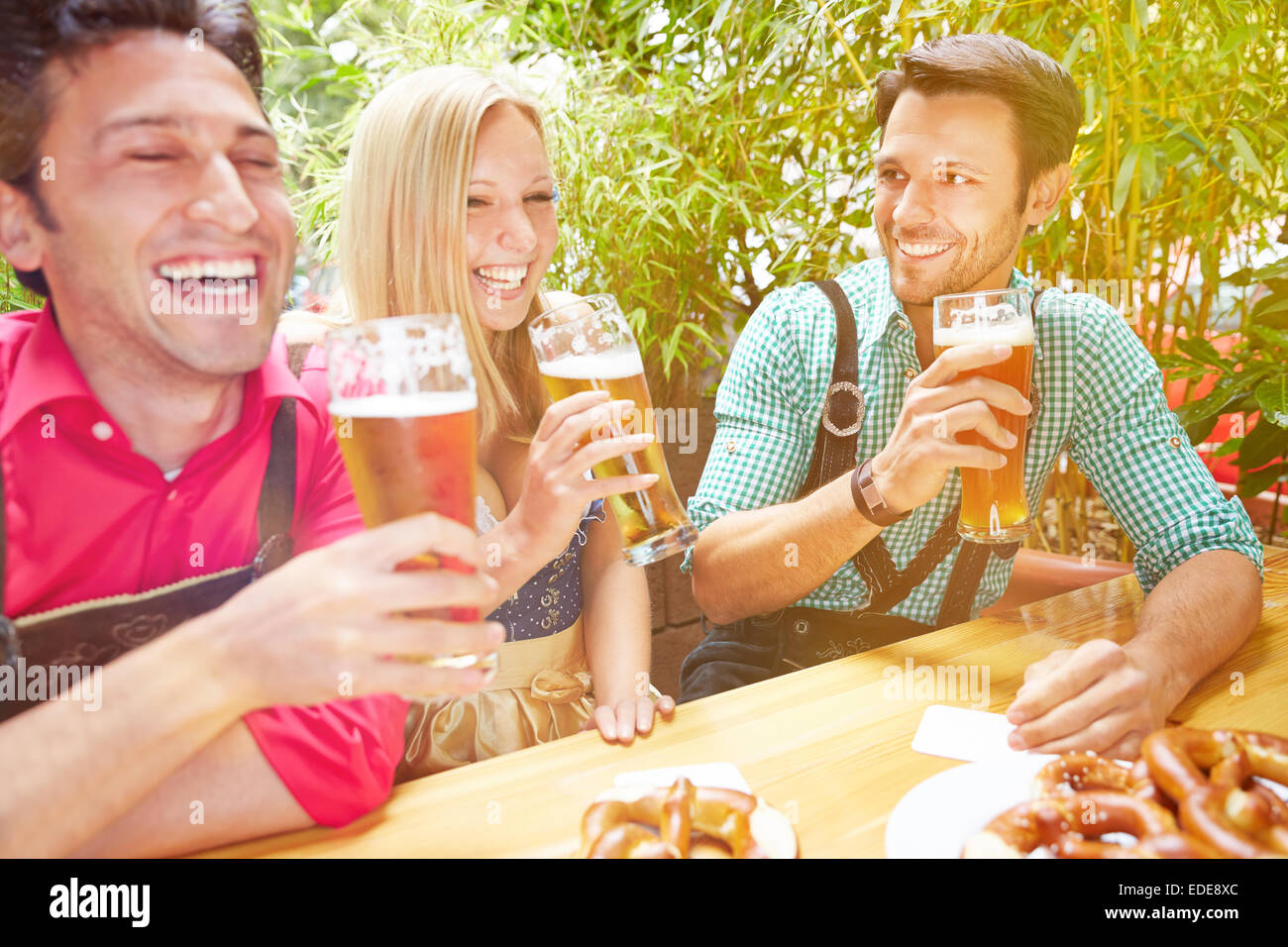 Happy amici ridendo nel giardino della birra in Baviera in estate Foto Stock