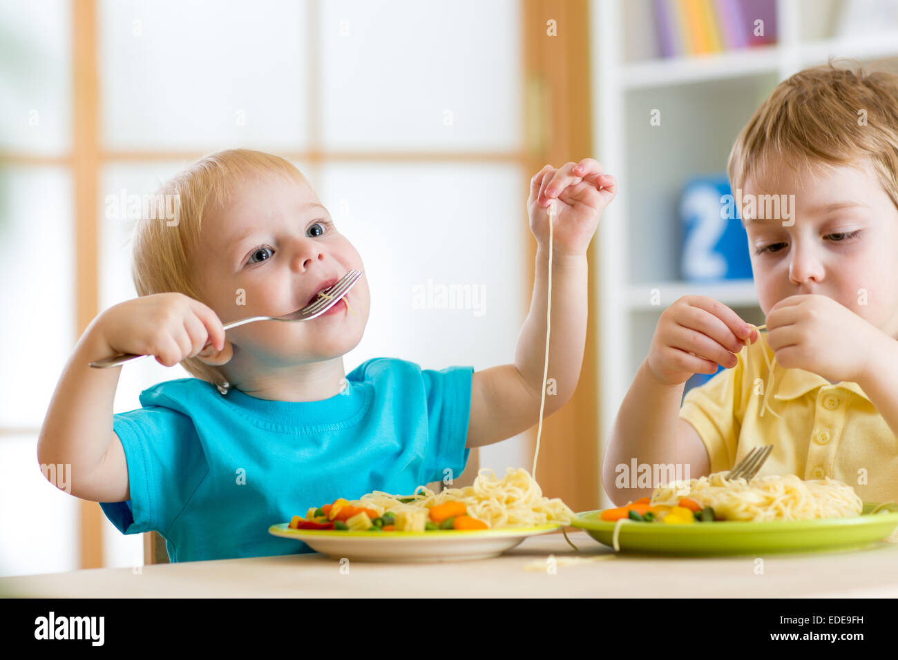 I bambini a mangiare in una scuola materna Foto Stock