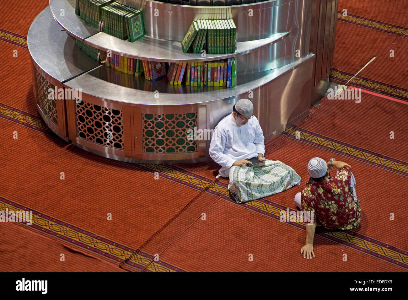 Musulmani smartphone il controllo presso la Moschea Istiqlal / Masjid Istiqlal, più grande moschea in Indonesia e nel Sud Est asiatico a Giacarta Foto Stock