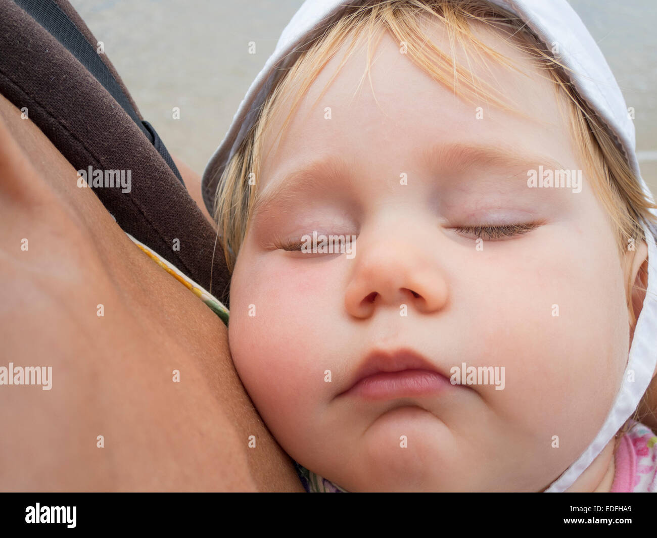 Vicino la faccia del bambino con cappello bianco dormire a zaino bracci mom Foto Stock