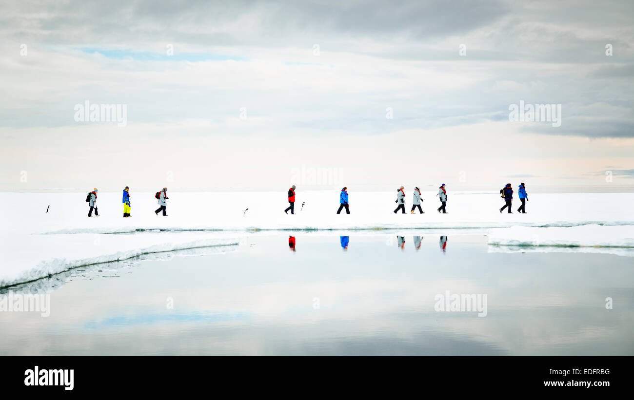 Passeggeri dal Akademik Shokalskiy una passeggiata sul ghiaccio con Adelie pinguini. Foto Stock