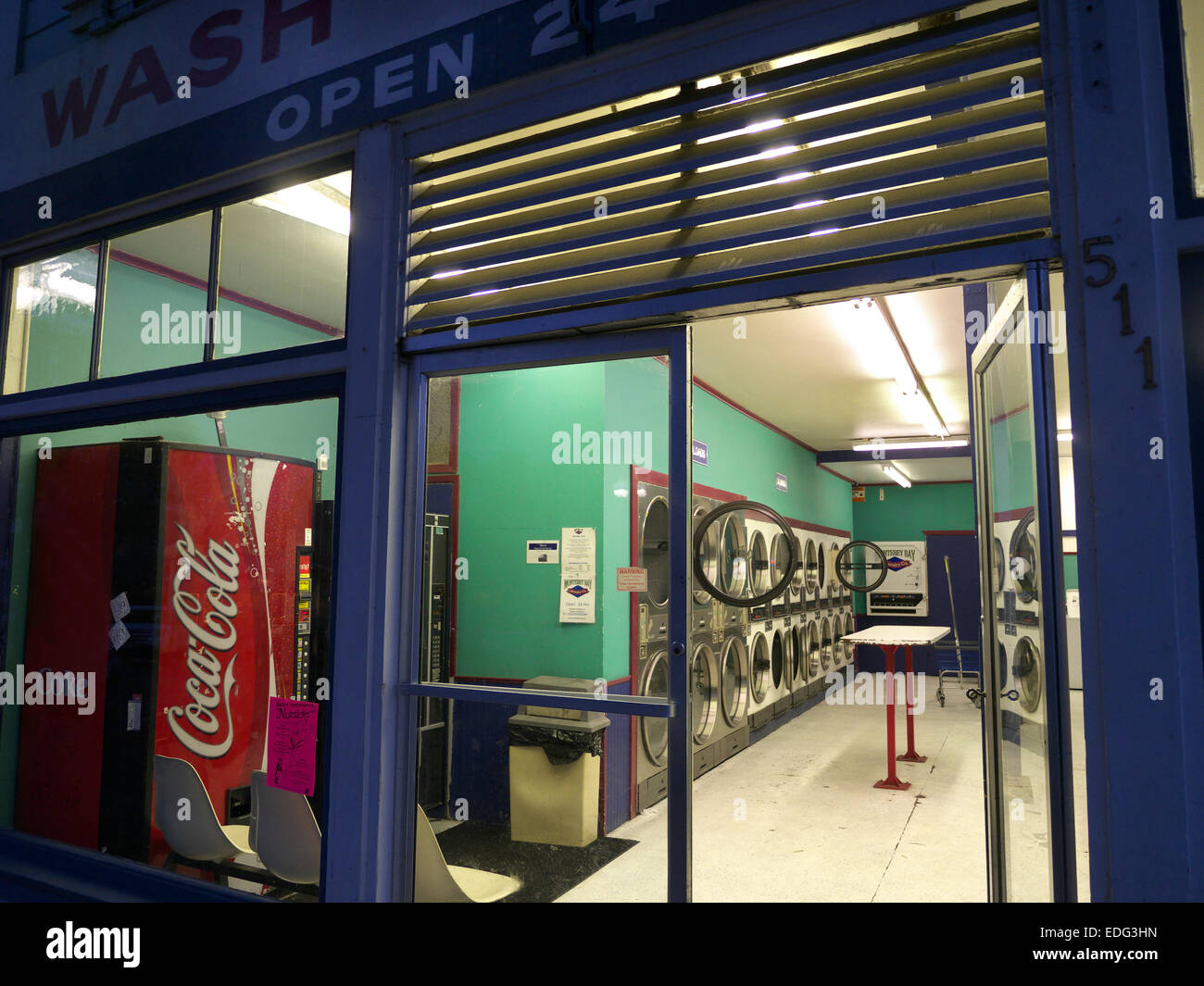 Lavanderia automatica a gettoni, lavanderia interna con sportello per lavatrice aperto e macchina Coca Cola di notte nella città americana di Pacific Grove California USA Foto Stock