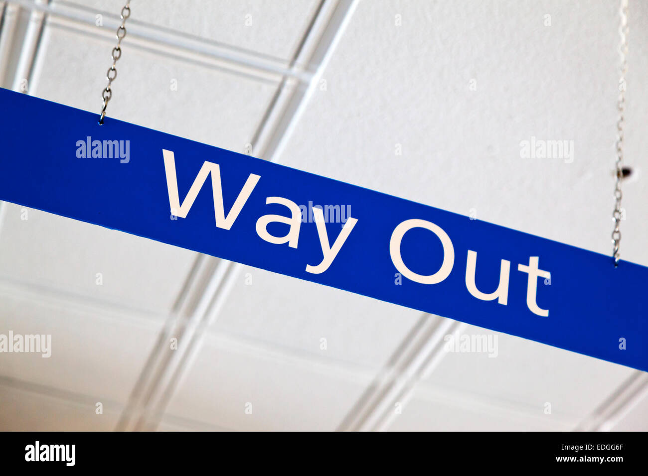 Blue Way Out segno appeso su una catena di metallo dal soffitto di un British National Health Service NHS hospital Foto Stock