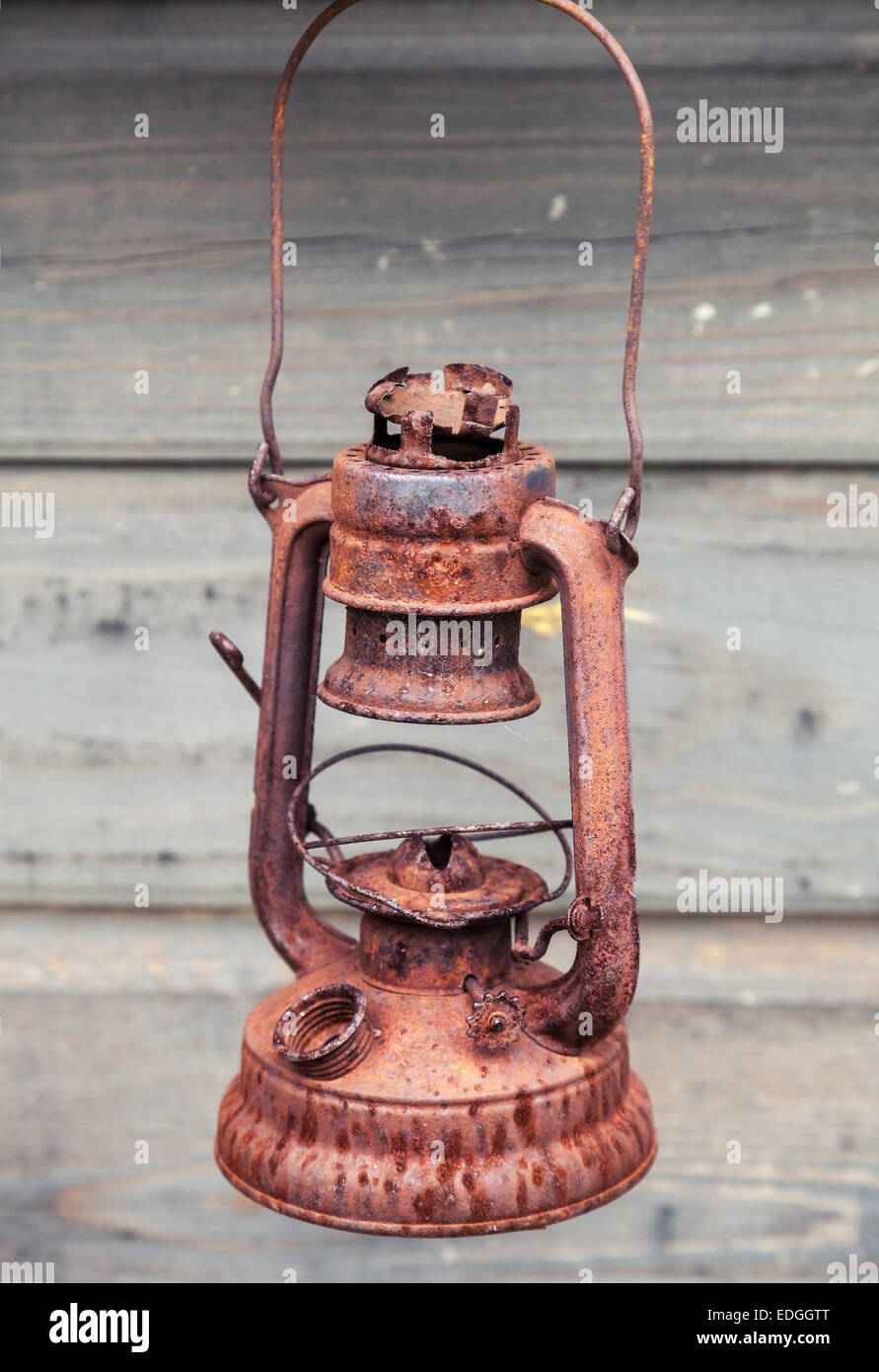 Vecchio arrugginito rosso lampada a kerosene su legno grigio Sfondo a parete Foto Stock