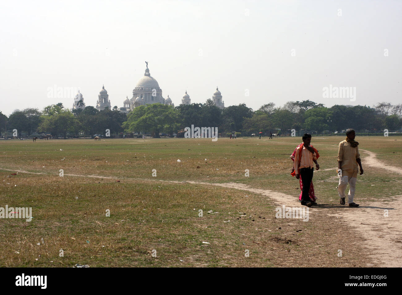 Uomini a piedi attraverso il Maidan, Kolkata (Calcutta), con il Victoria Memorial dietro di loro Foto Stock