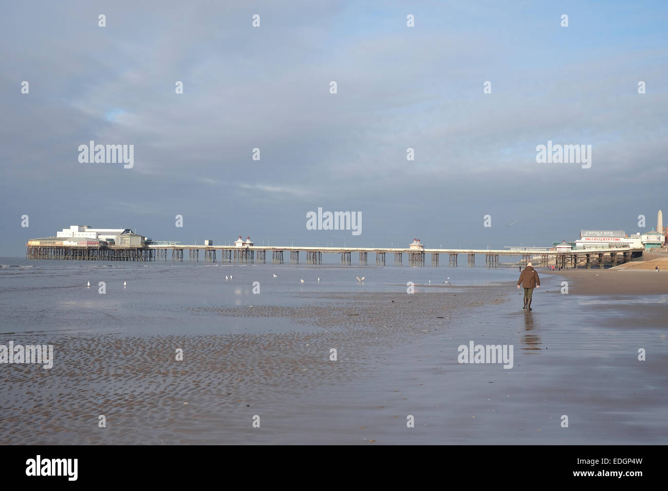 Uomo a camminare lungo la spiaggia di Blackpool verso North Pier Foto Stock