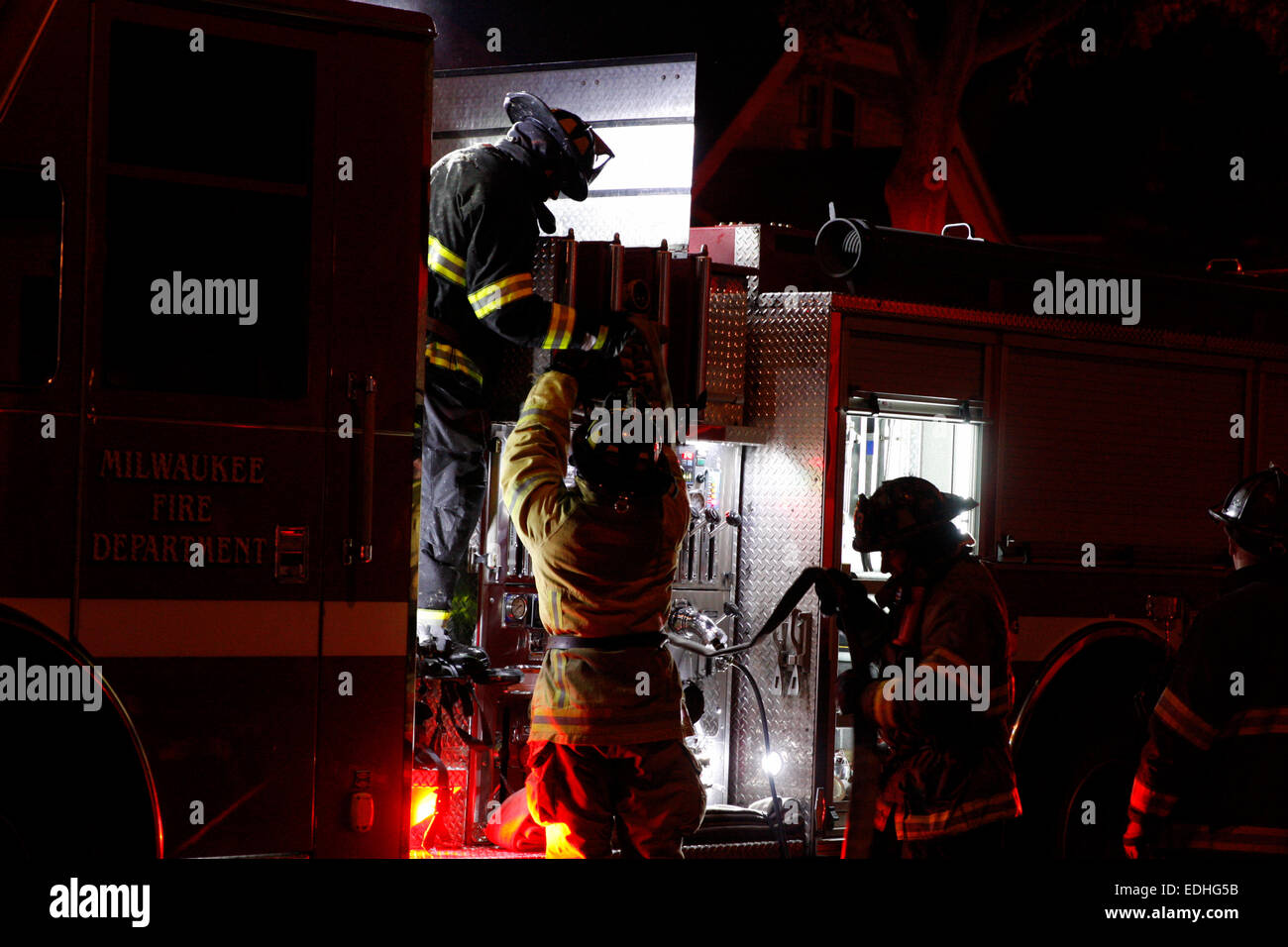 Milwaukee Vigili del Fuoco vigili del fuoco di MFD imballare il tubo antincendio su un motore da una casa chiamata di incendio Foto Stock