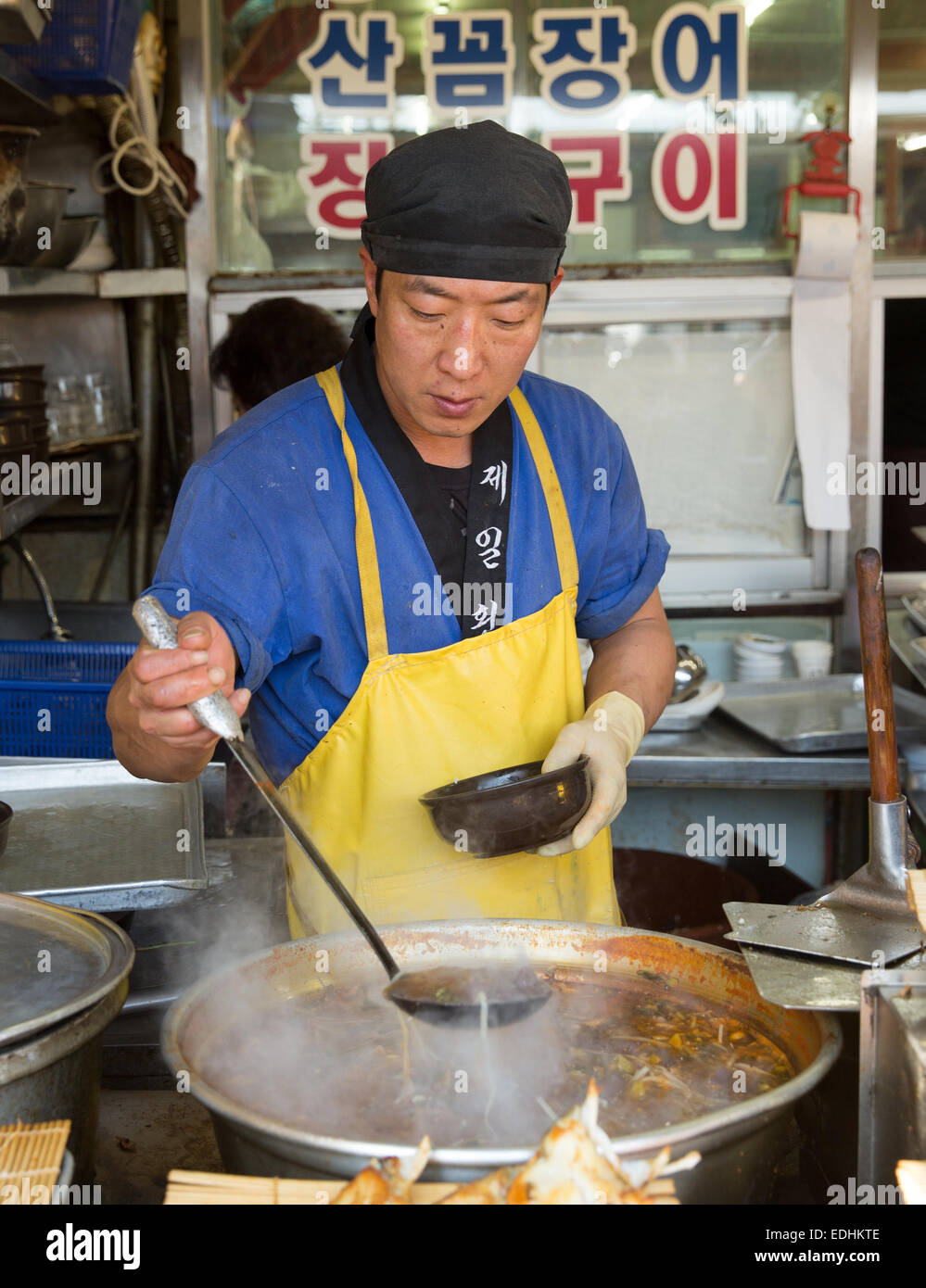 L'uomo serve cibo caldo a Jagalchi mercato del pesce, Busan, della Repubblica della Corea del Sud Foto Stock