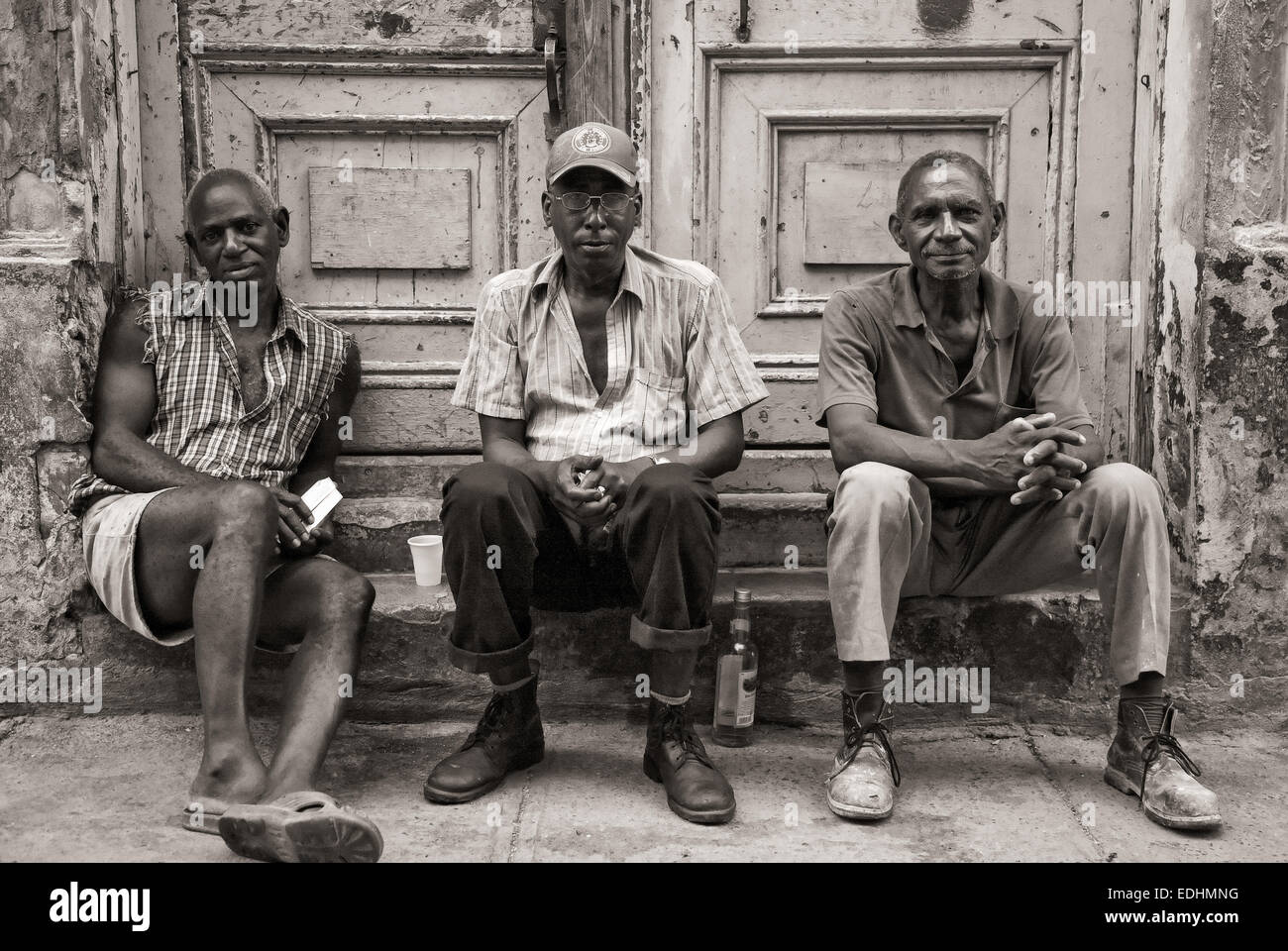 Cuba Street Archivio. Tre uomini cubani seduti sul portale nella vecchia Havana. Foto Stock