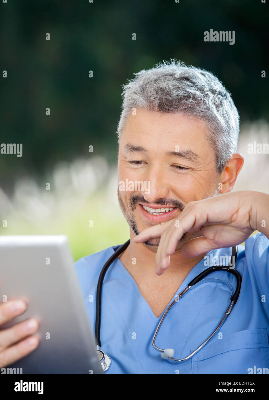 Medico maschio sorridere mentre guardando il computer tablet Foto Stock