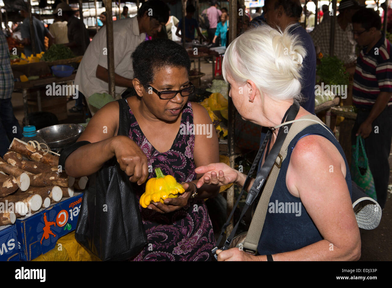 Mauritius Quatre Bornes, mercato locale, donna spiegando Pattypan Squash al visitatore occidentale Foto Stock