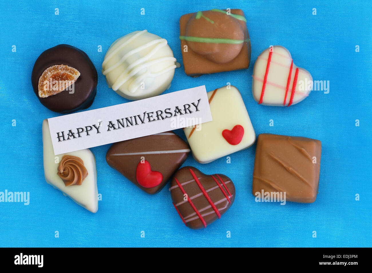 Felice anniversario card con cioccolatini su sfondo blu Foto Stock