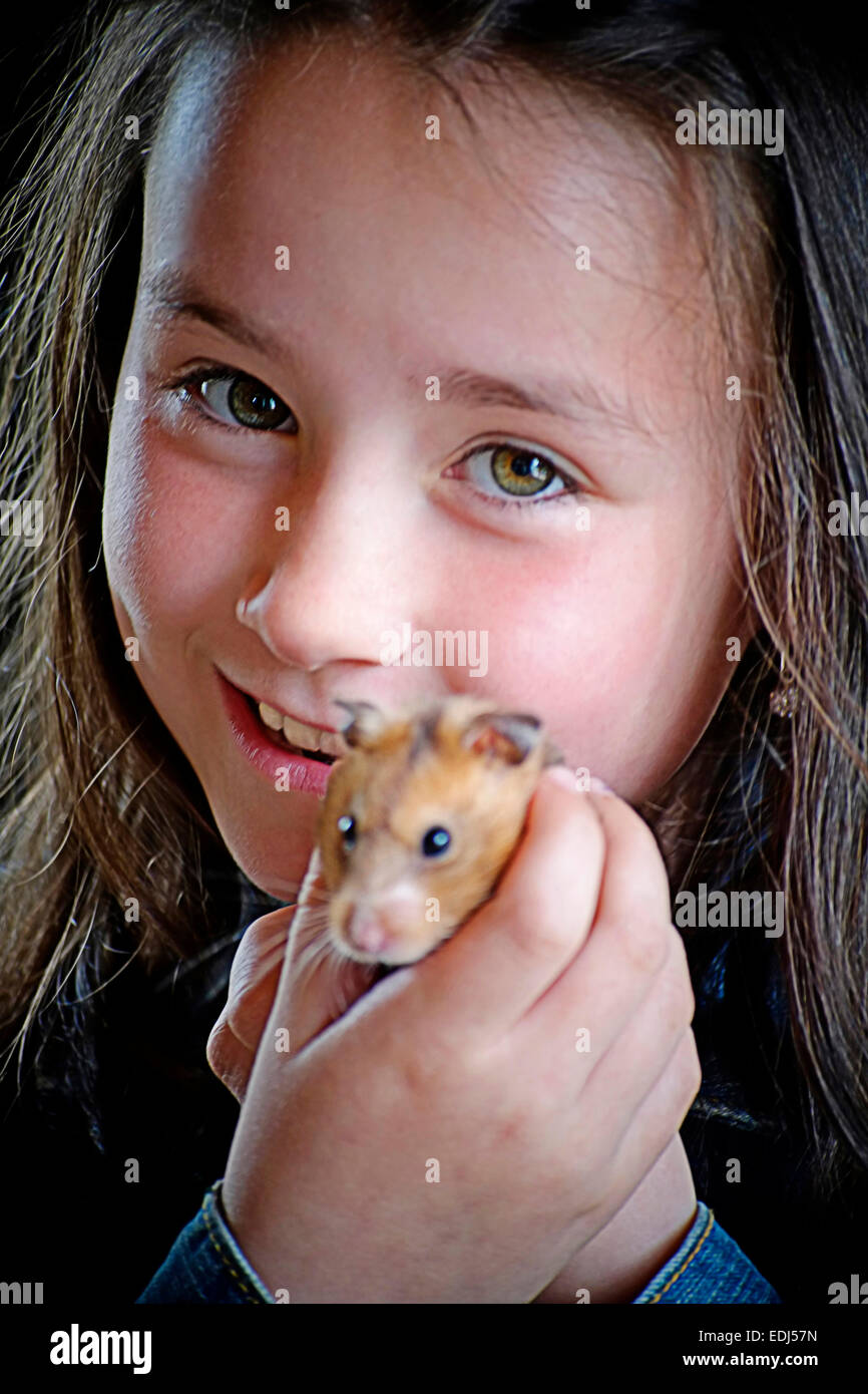 Un sorridente ragazza giovane trattiene il suo animale domestico hamster fino per la fotocamera Foto Stock