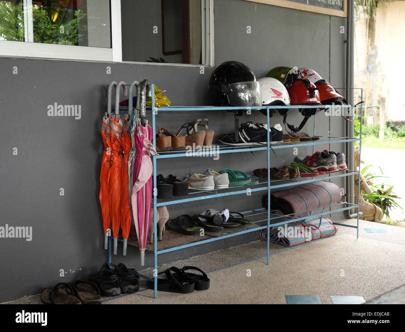 Rack con caschi per noleggiato scooter, scarpe, ombrelli, in hotel, Thailandia, Sud-est asiatico. Foto Stock