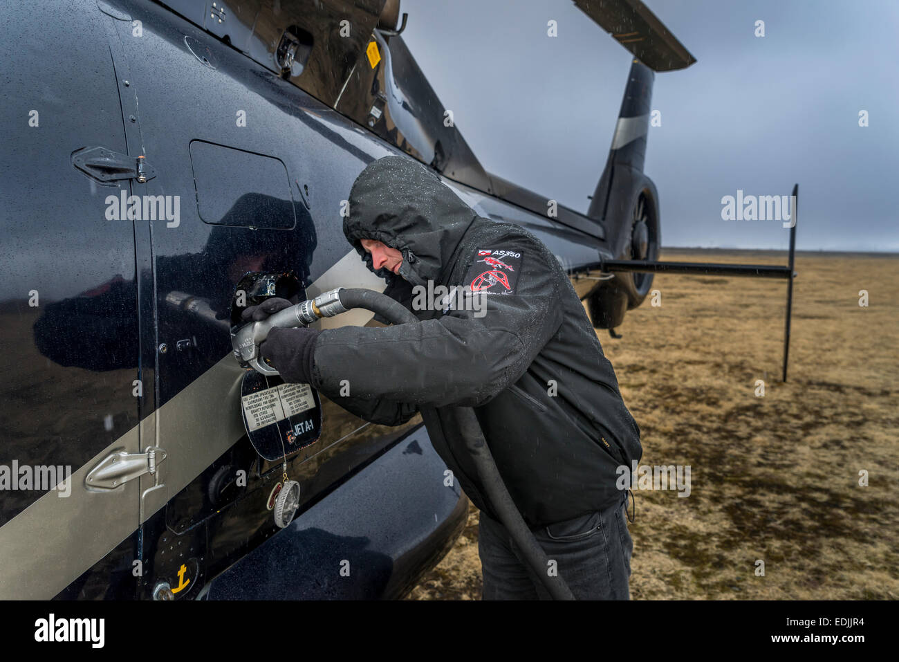 Pilota di mettere carburante in un elicottero, south coast, Islanda Foto Stock