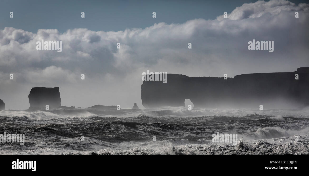 Onde che si infrangono sulla riva con Dryholaey in background, Islanda. Dyrholaey tradotto significa "il foro della porta isola " Foto Stock