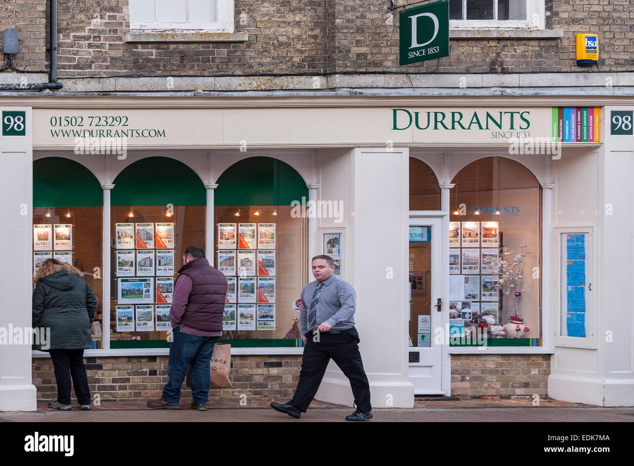 Le persone che cercano nella finestra di Durrants agente immobiliare a Southwold , Suffolk , Inghilterra , Inghilterra , Regno Unito Foto Stock