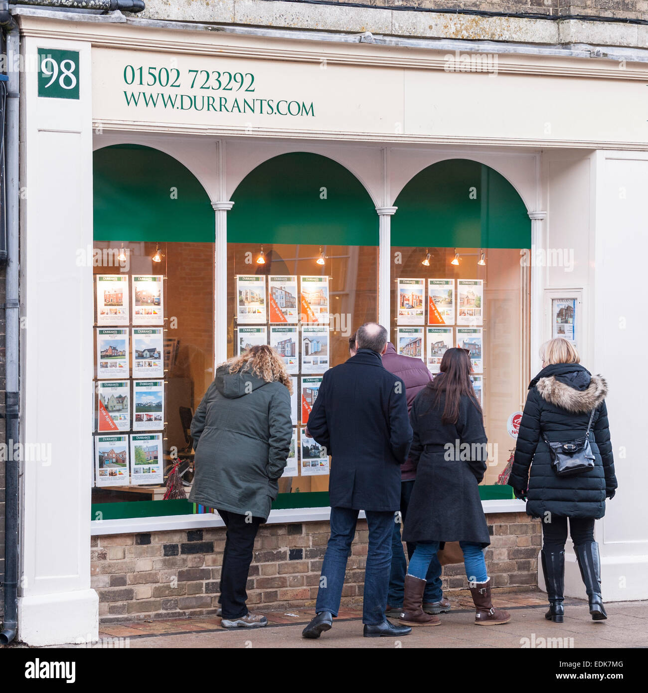 Le persone che cercano nella finestra di Durrants agente immobiliare a Southwold , Suffolk , Inghilterra , Inghilterra , Regno Unito Foto Stock