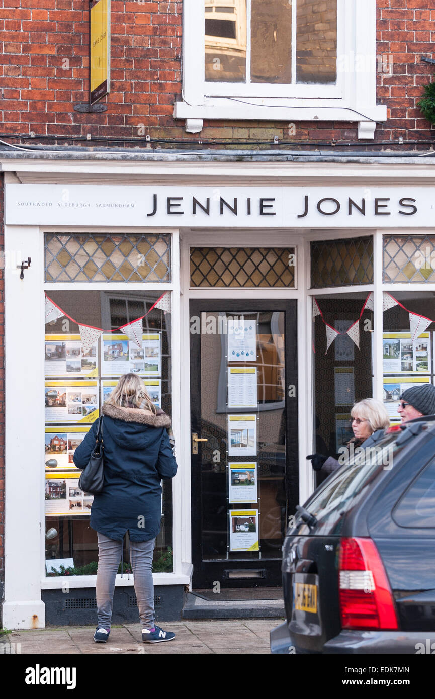 Una donna che guarda nella finestra di Jennie Jones agente immobiliare a Southwold , Suffolk , Inghilterra , Inghilterra , Regno Unito Foto Stock