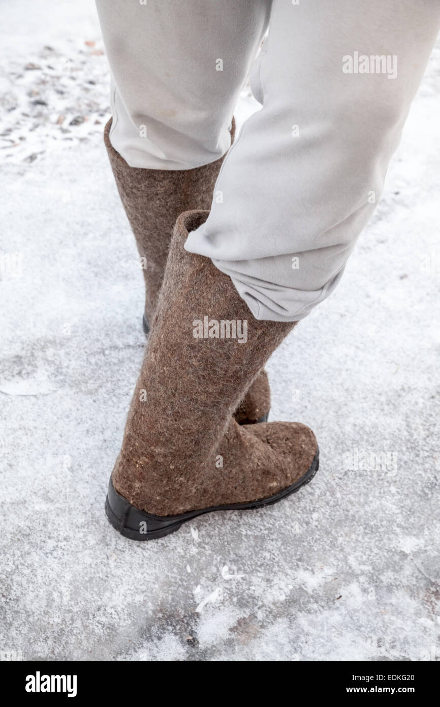 Piedini maschio con tradizionale russo stivali di feltro stand su strada in inverno con neve e ghiaccio Foto Stock
