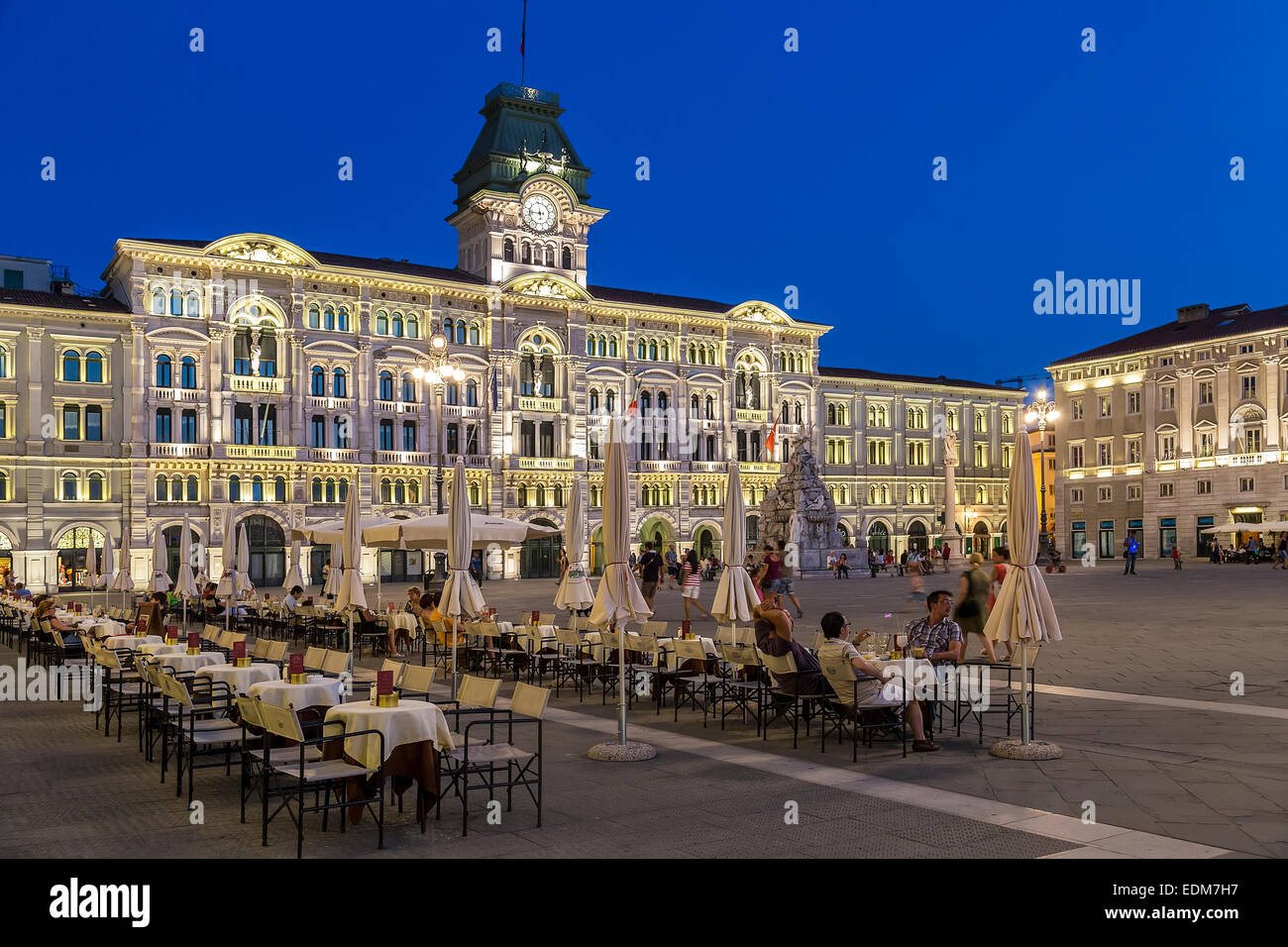 Persone al ristorante tavoli in Piazza Unità d'Italia con il palazzo comunale dietro, Trieste, Italia Foto Stock