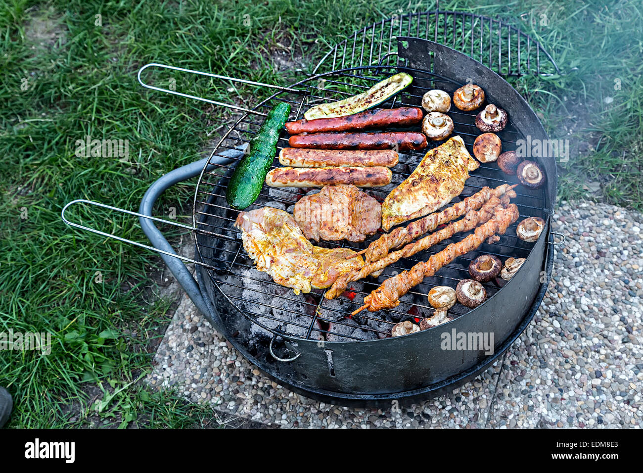 La cottura della carne sul piccolo barbecue grill Foto Stock
