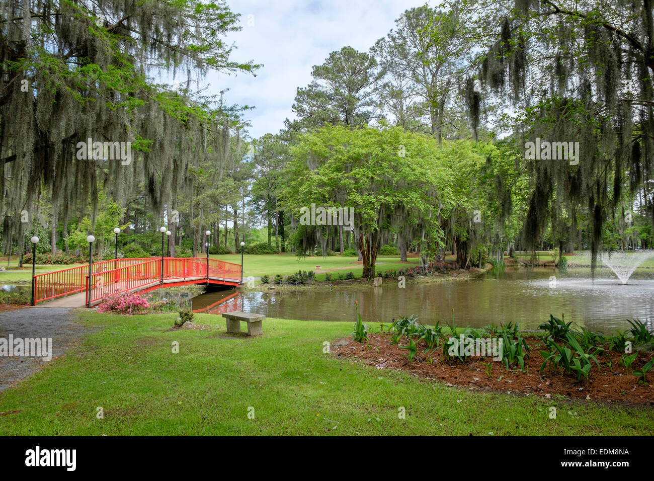 Il tranquillo giardino del CAFFCO Floral Outlet, con un lago e un ponte pedonale rosso a Wetumpka, Alabama, USA. Foto Stock
