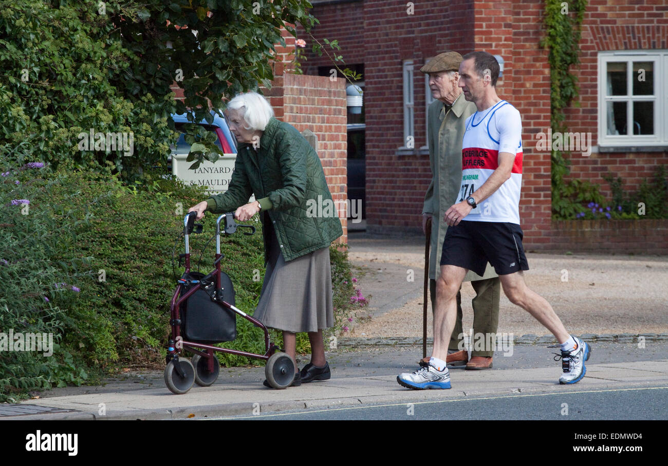 Due anziani su una Domenica mattina e runner a piedi all'inizio di una corsa su strada Foto Stock