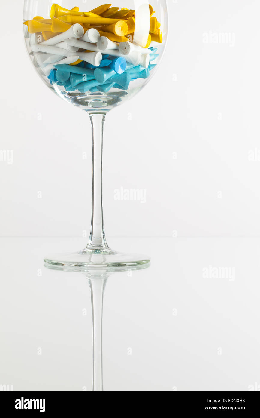 Un bicchiere di vino e attrezzature da golf sulla scrivania in vetro Foto Stock