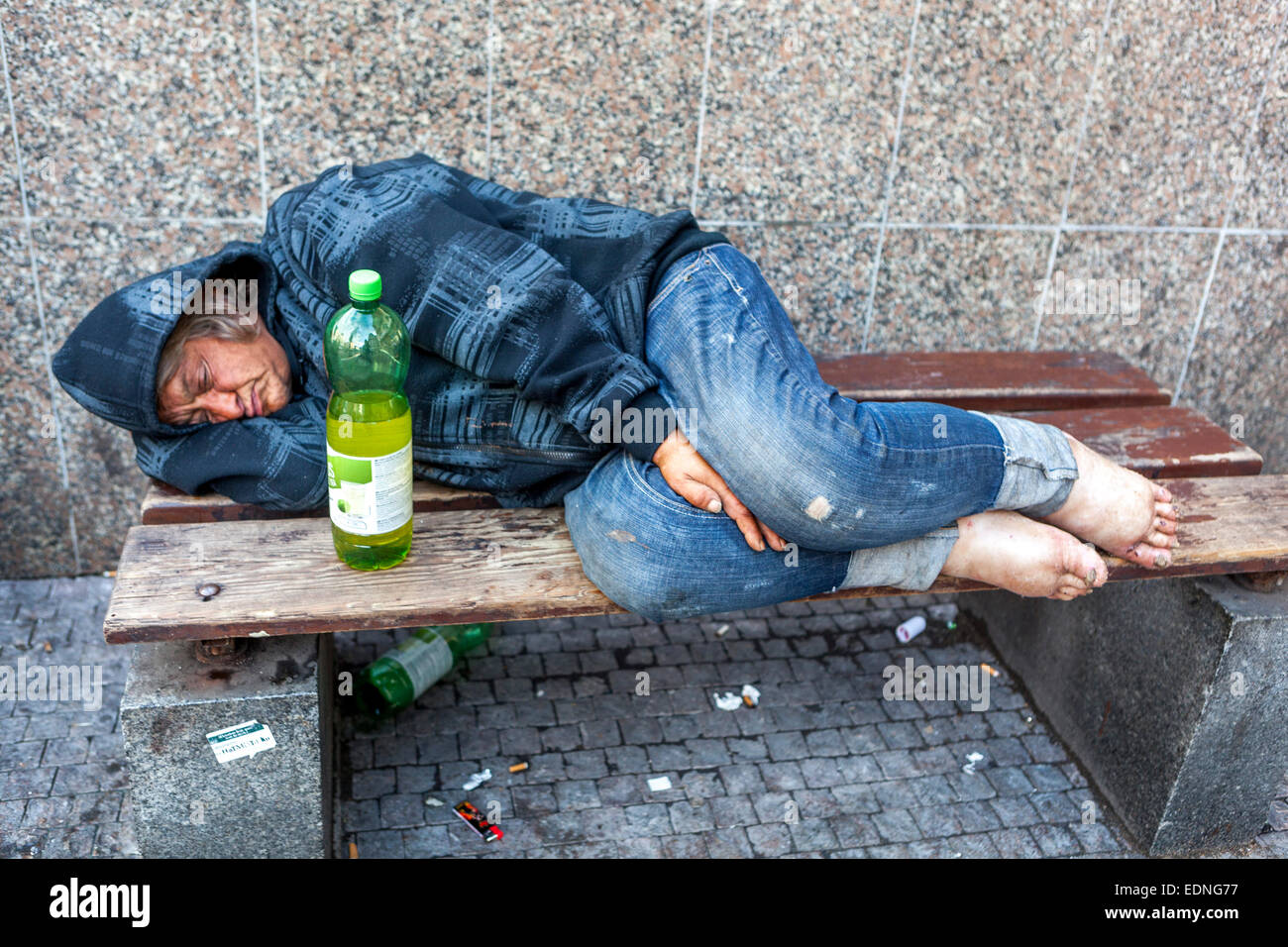 Un ubriaco addormentato senzatetto sulla strada sdraiato su una panchina, persona in Piazza Venceslao, Praga, Repubblica Ceca Foto Stock