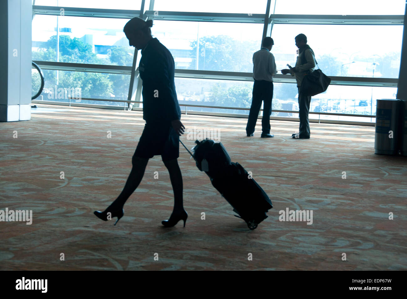 India Delhi airport - sala partenze- hostess con borsa su ruote e alta scarpe con tacco Foto Stock