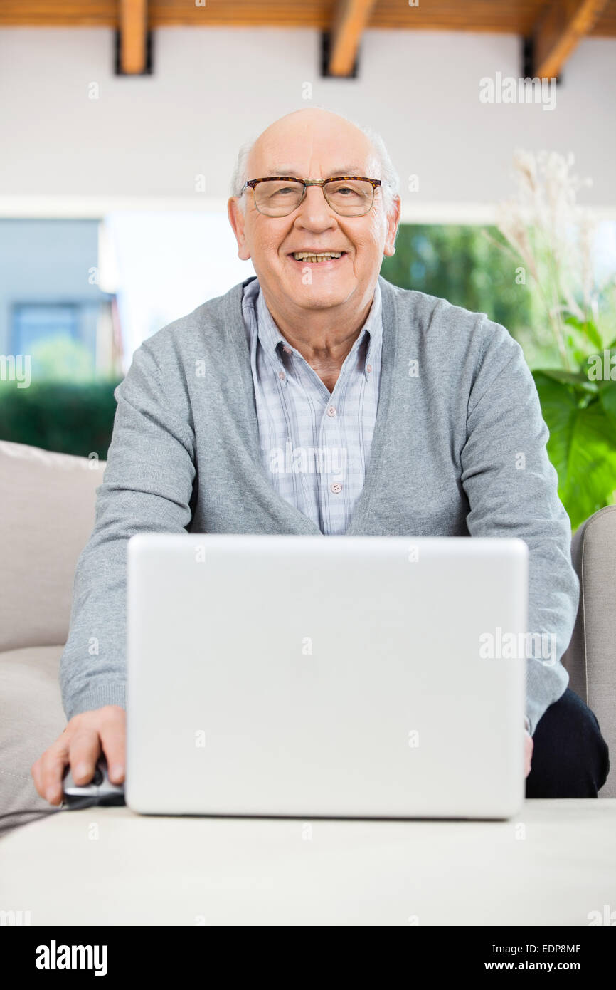 Felice l'uomo senior con computer portatile presso la casa di cura portico Foto Stock