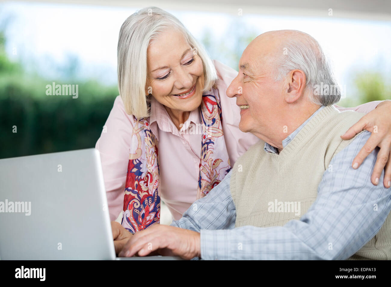 Sorridente coppia Senior guardando ogni altra durante l'utilizzo di Laptop Foto Stock