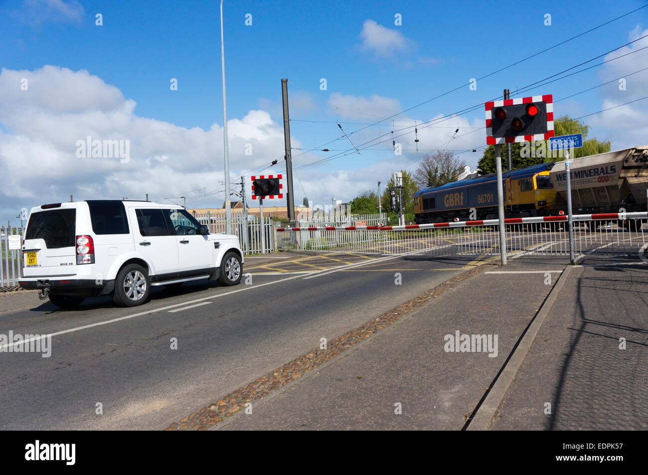 White Land Rover Discovery attende per un treno di merci a Tennyson Avenue passaggio a livello immediatamente fuori King's Lynn stazione. Foto Stock