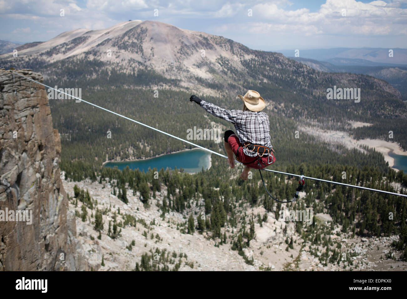 Highliner maschio nel cappello da cowboy si alza su un piede 125 highline su un lago in un gap sulla parte superiore della cresta Mammut Foto Stock