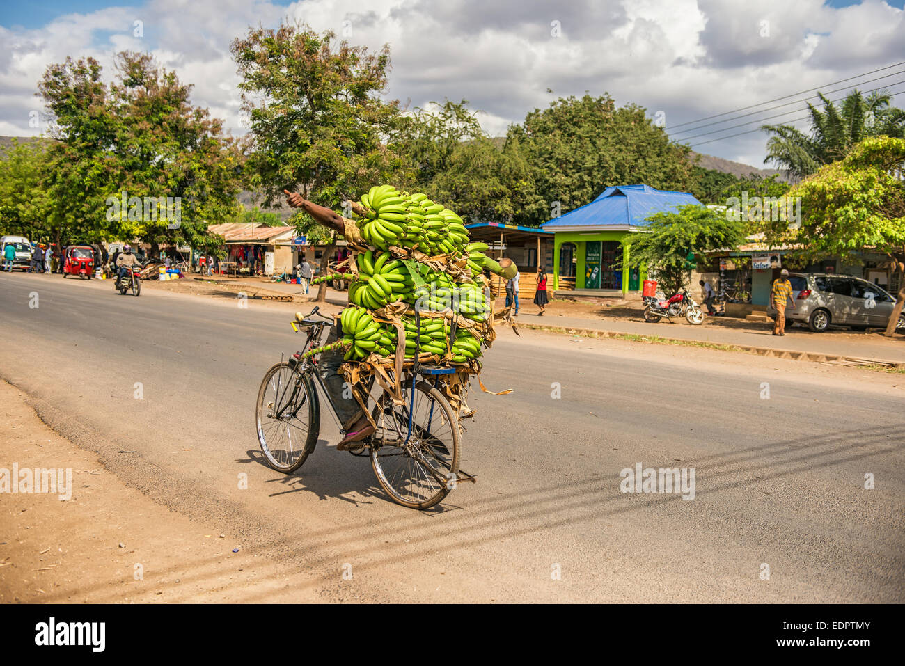 L'uomo africano viaggiando su una moto con un mazzetto di banane Foto Stock