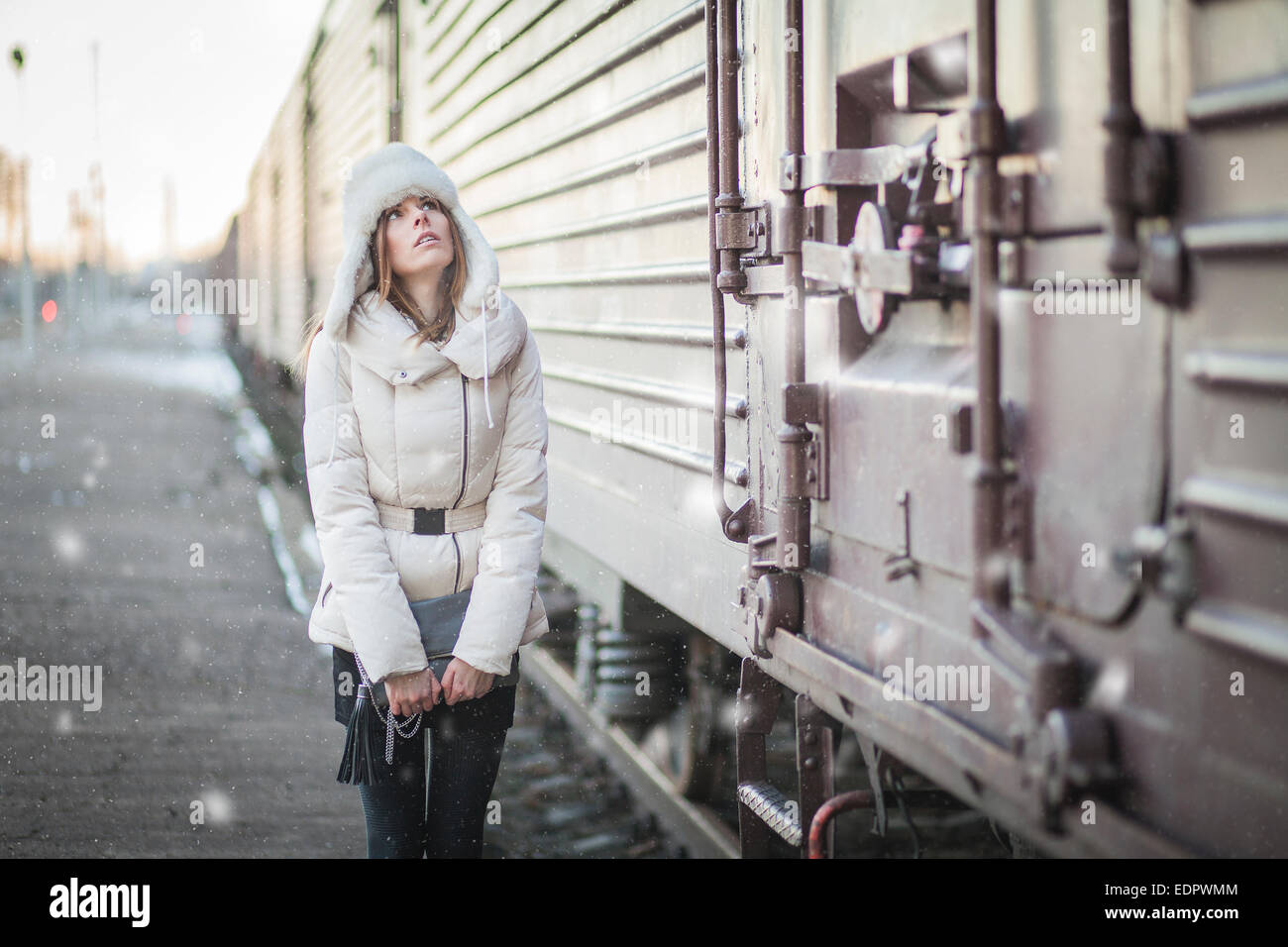 Giovane donna nel cappello di pelliccia e down jacket su una stazione ferroviaria Foto Stock