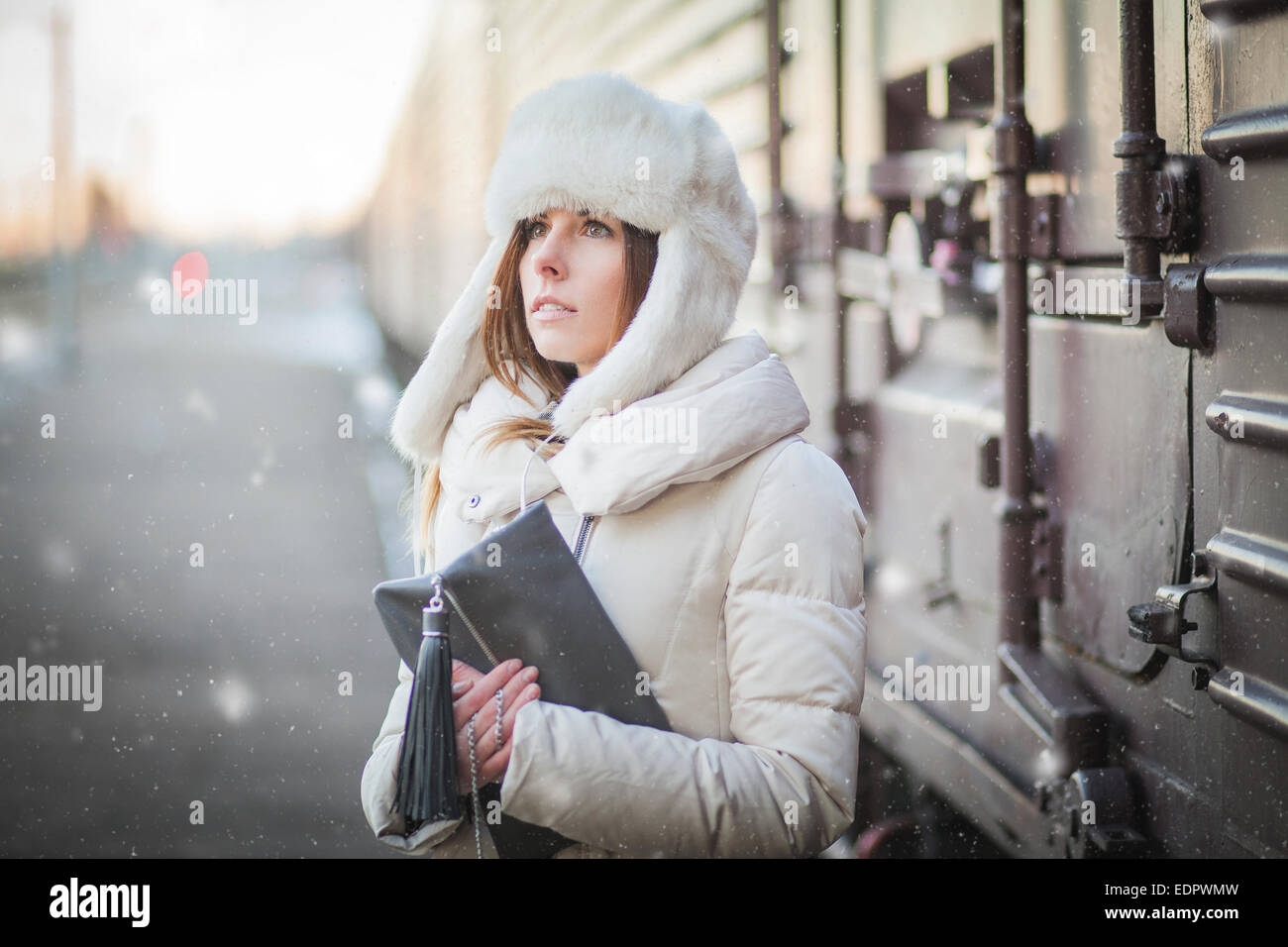 Giovane donna nel cappello di pelliccia e down jacket in prossimità del trasporto merci Foto Stock